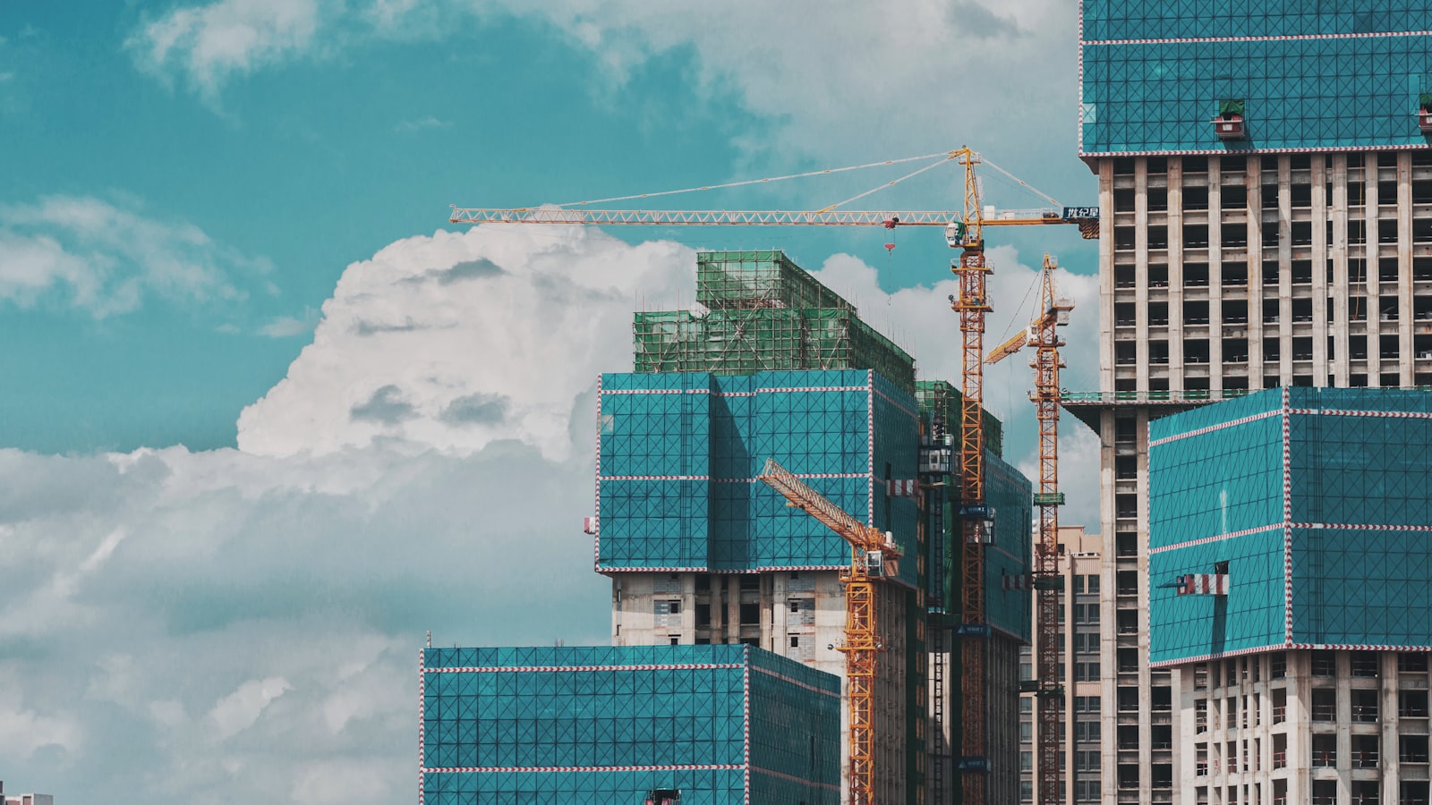 Immeubles en construction enveloppés de bâches, grues au travail entre les tours.